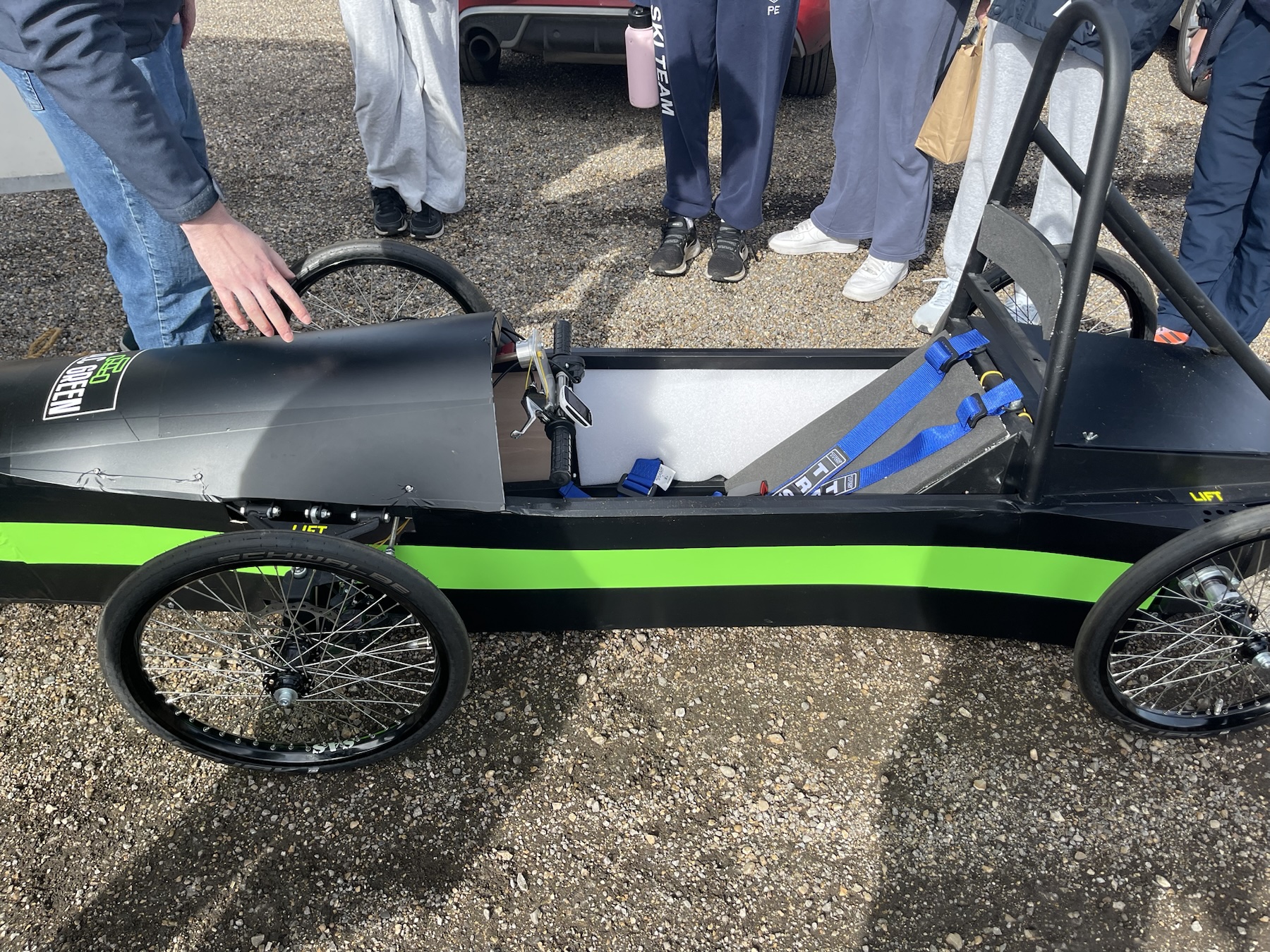 Side view of the school’s black electric race car with a green stripe at Mallory Park